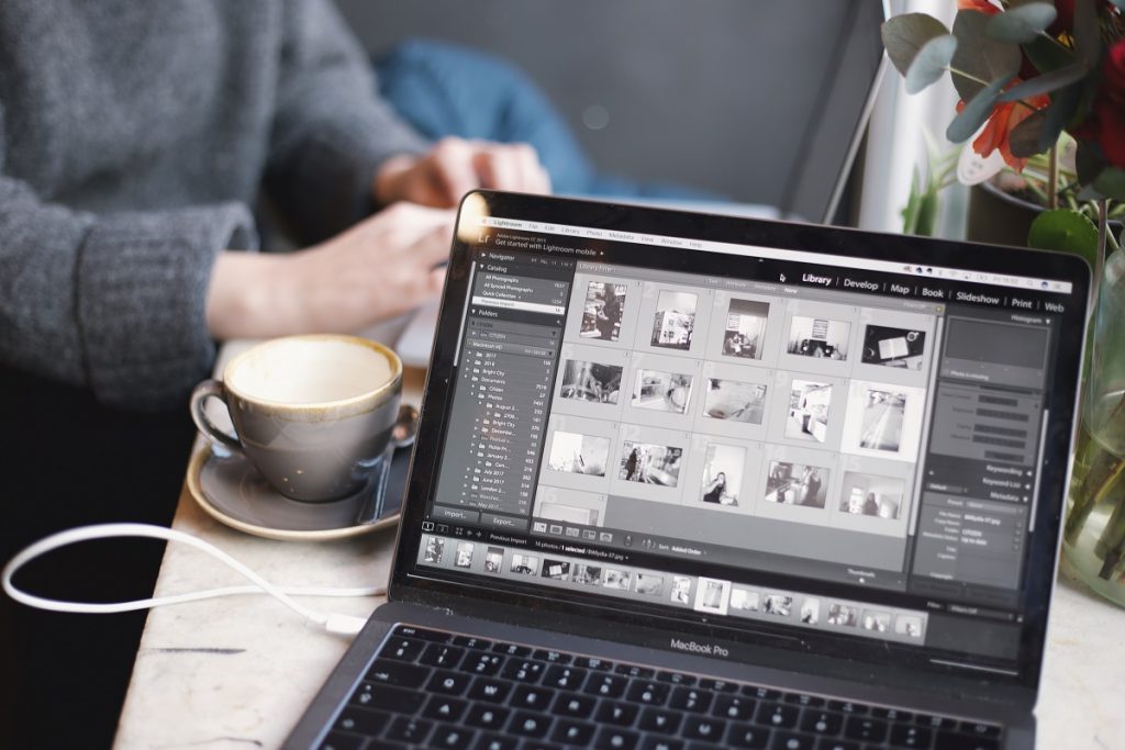 Editing photos using laptop with a cup of coffee on the side
